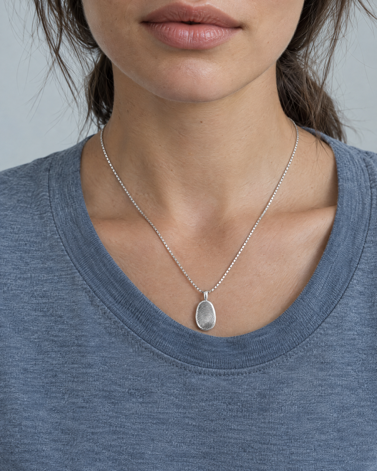 Sterling silver fingerprint necklace worn with a grey-blue tee